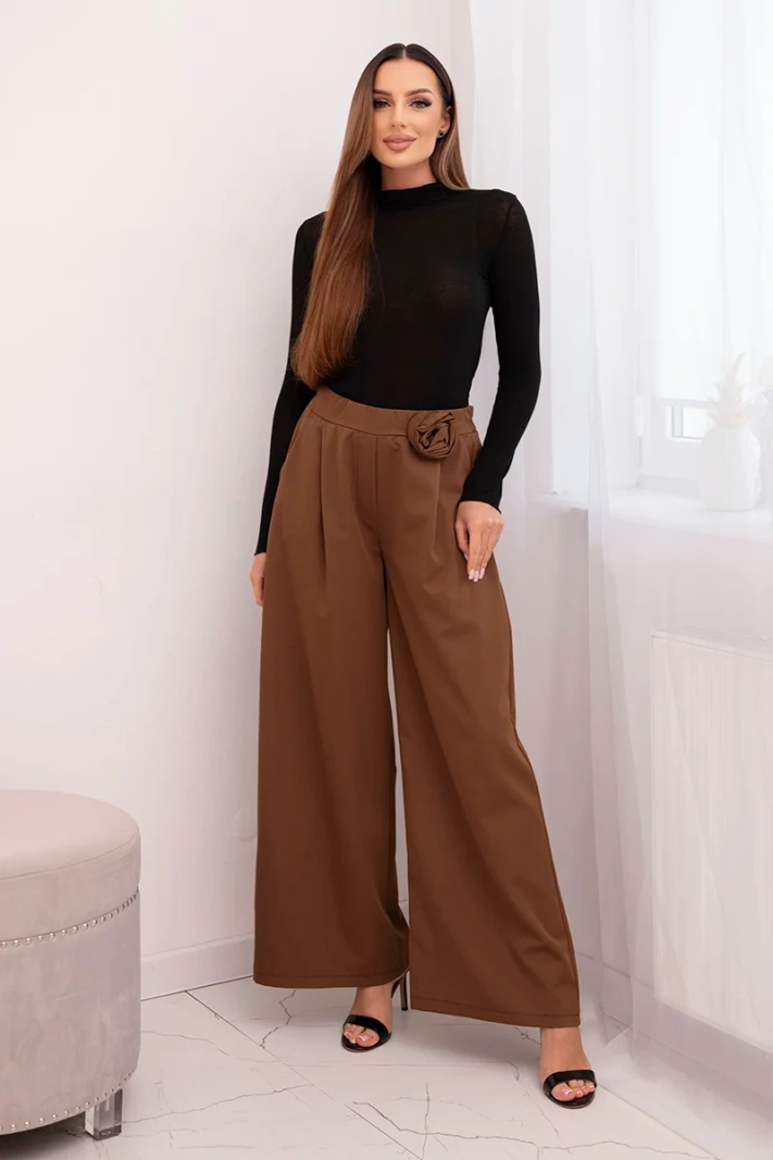 Elegant women's trousers with wide legs and a decorative flower light brown